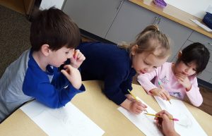 kids seated table pencil work thinking