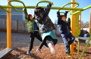 three kids hanging off ground bars playground